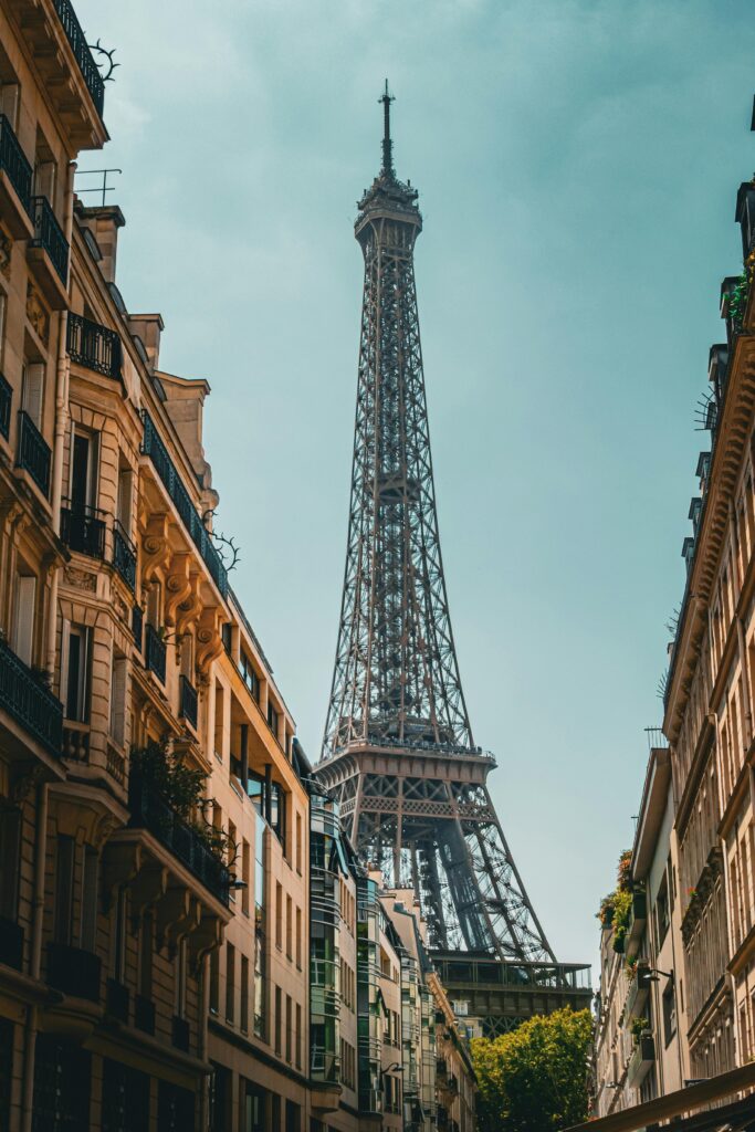 Iconic Eiffel Tower view from a Parisian street, highlighting classic French architecture under a clear sky.